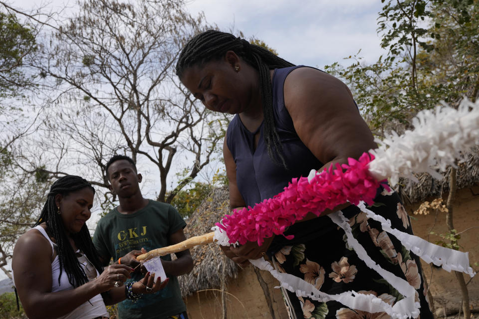 Members of the Kalunga quilombo, the descendants of runaway slaves, prepare the decoration of the masts, during the culmination of the week-long pilgrimage and celebration for the patron saint "Nossa Senhora da Abadia" or Our Lady of Abadia, in the rural area of Cavalcante in Goias state, Brazil, Saturday, Aug. 13, 2022. Devotees celebrate Our Lady of Abadia at this time of the year with weddings, baptisms and by crowning distinguished community members, as they maintain cultural practices originating from Africa that mix with Catholic traditions. (AP Photo/Eraldo Peres)