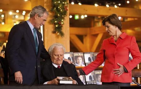 Former U.S. President George W. Bush (L) gives a copy of his new book "Decision Points" to Billy Graham (C) as Laura Bush looks on at the Billy Graham Library in Charlotte, North Carolina December 20, 2010. REUTERS/Chris Keane