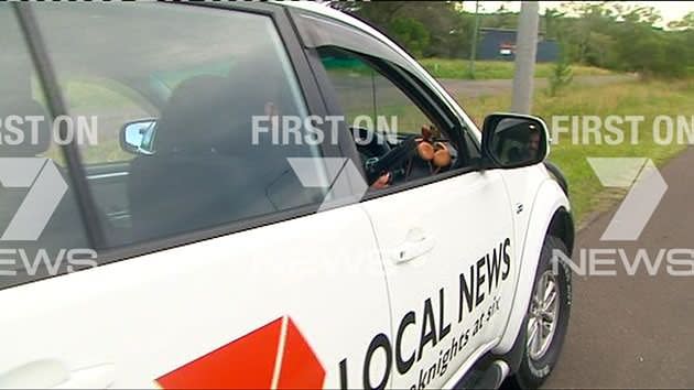 Man brandishes a replica gun before driving away in the 7News car. Source 7News