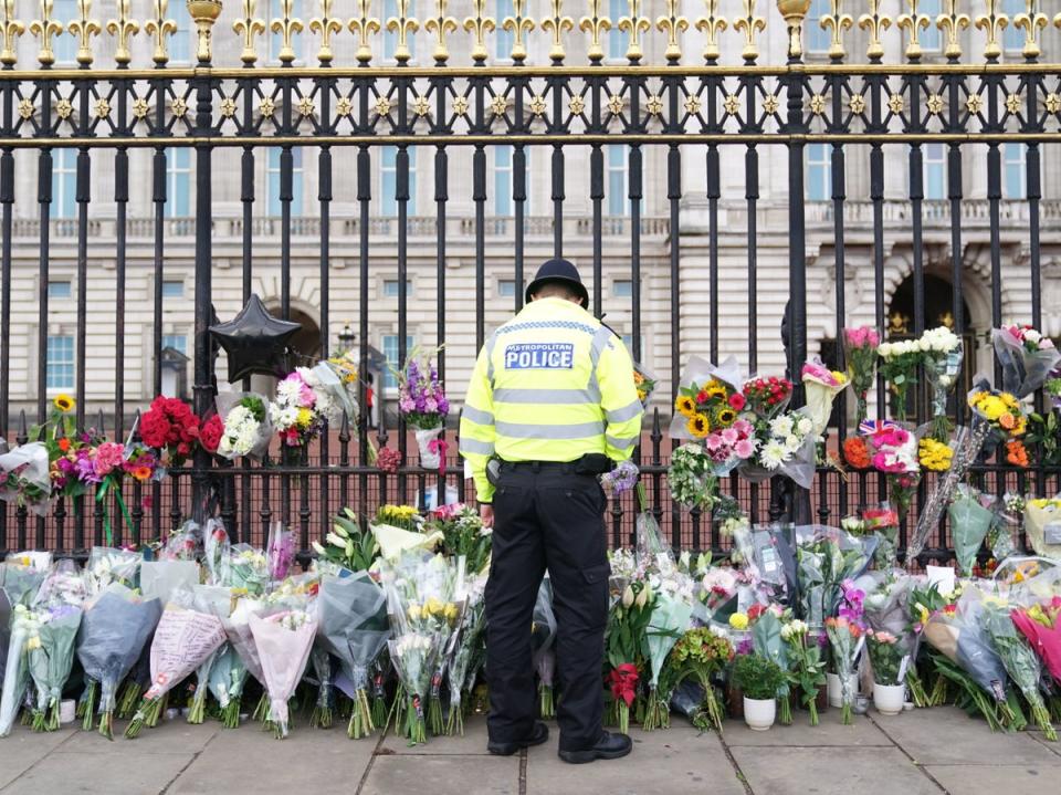 Un agente de policía observa las flores depositadas ante el Palacio de Buckingham tras la muerte de la reina Isabel II el jueves (PA)