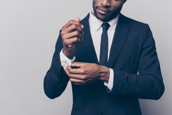 A man adjusting the sleeve on a suit.