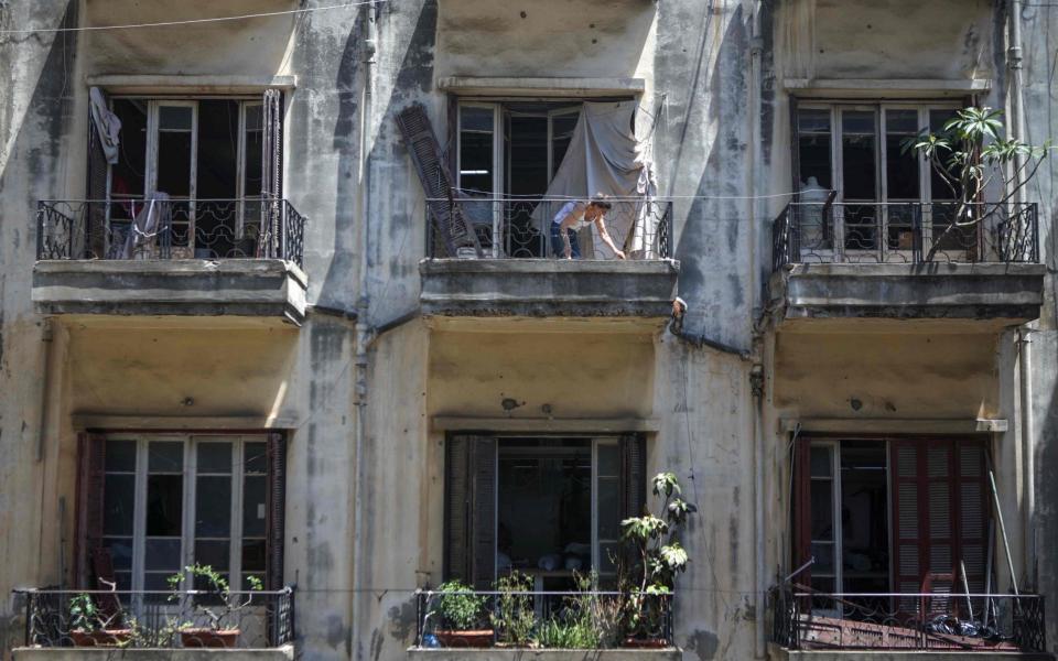 A Lebanese woman removes rubble from her damaged apartment in the Beirut neighbourhood of Gemmayzeh - PATRICK BAZ /AFP