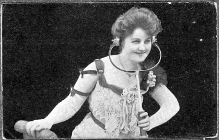 A young woman of the early 20th century listening to Electrophone through headphones