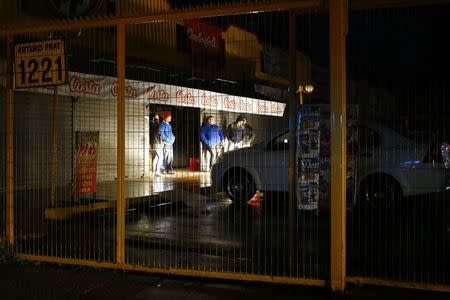 People gather outside a store along a street during a blackout, after an earthquake hit Chile's central zone, in Santiago, August 23, 2014. REUTERS/Ivan Alvarado