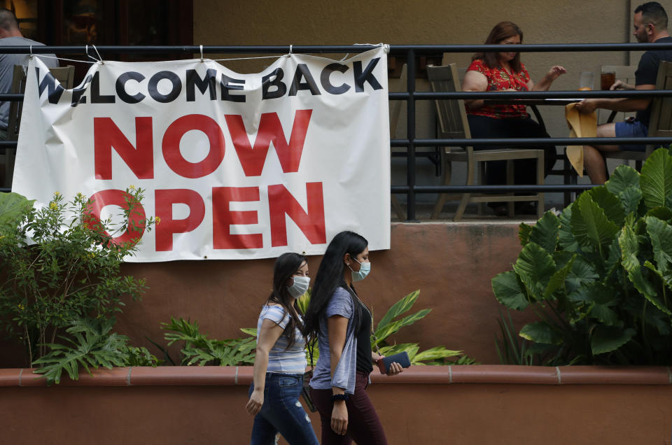 FILE - In this May 27, 2020, file photo, visitors to the River Walk pass a restaurant that has reopened in San Antonio. Coronavirus cases are rising in nearly half the U.S. states, as states are rolling back lockdowns. (AP Photo/Eric Gay, File)