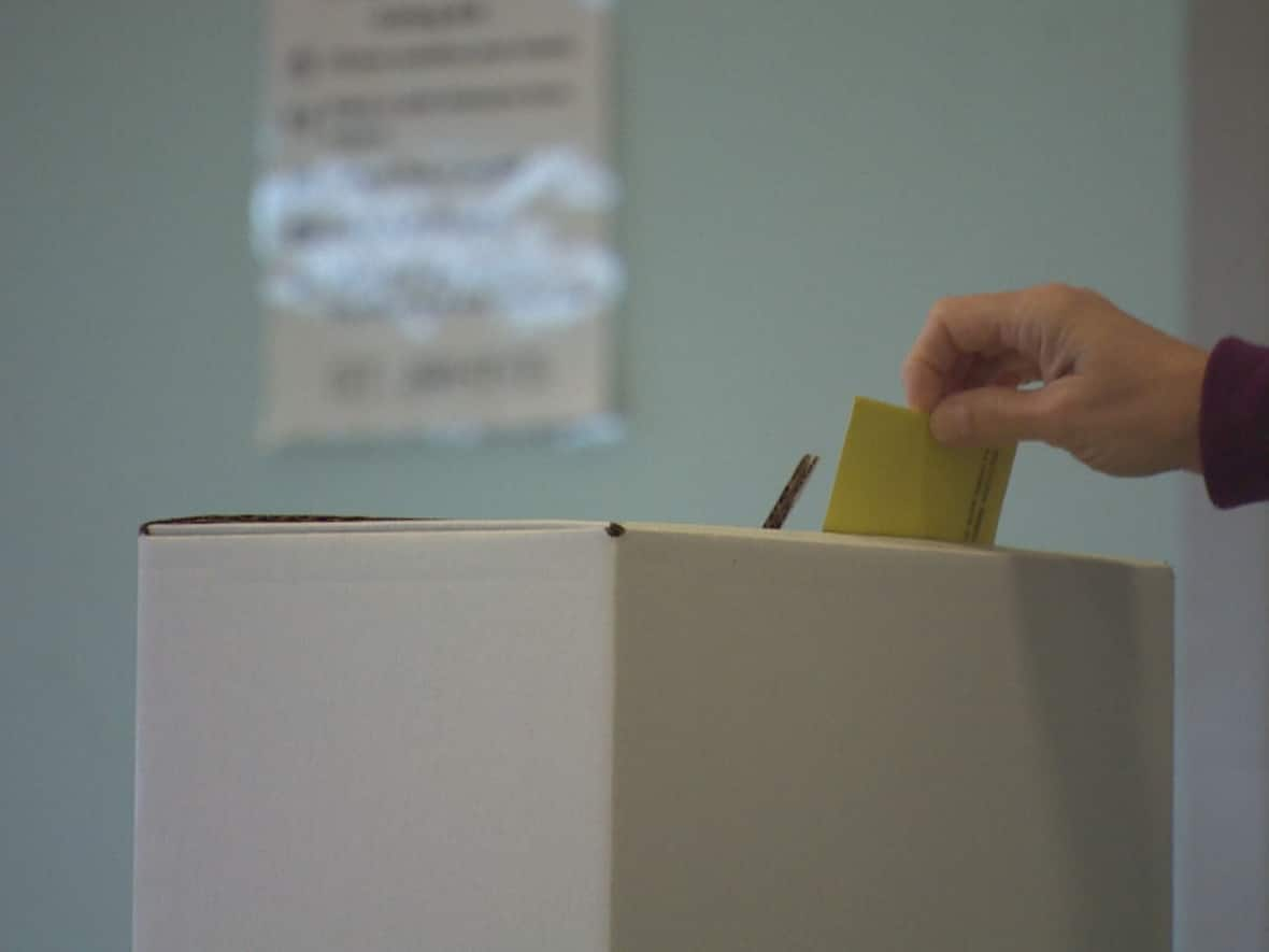 A voter drops their ballot into a box in this file photo from a 2021 municipal election in St. Johns, Newfoundland. Municipal elections in five N.W.T. communities, and school board trustee elections in Yellowknife, are taking place on Monday. (Curtis Hicks/CBC - image credit)