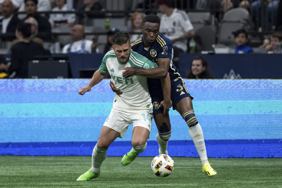 Austin FC's Diego Rubio, left, and Vancouver Whitecaps' Sam Adekugbe (3) vie for the ball during the first half of an MLS soccer match in Vancouver, British Columbia, on Saturday, May 4, 2024. (Ethan Cairns/The Canadian Press via AP)