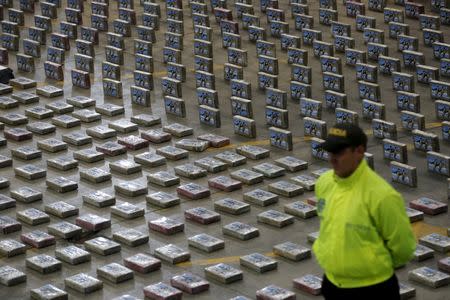 FILE PHOTO - A Colombian anti-narcotics policeman stands guard next to packs of cocaine at the police base in Bogota July 22, 2015. REUTERS/ John Vizcaino