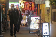 FILE - People wearing face masks to help protect against the spread of the coronavirus walk on a street lined with bars and restaurants in Tokyo on Jan. 19, 2022. Restaurants and bars will close early in Tokyo and a dozen other areas across Japan beginning Friday, Jan. 21, 2022 as Japan widens COVID-19 restrictions due to omicron causing cases to surge to new highs in metropolitan areas. (AP Photo/Koji Sasahara, File)