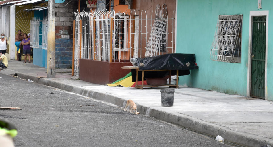 Black plastic covers a person's body outside a Guayaquil home.