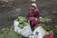 A vendor wearing a face mask as a precaution against the coronavirus waits for customers while selling vegetable leaves at a market in Hyderabad, India, Thursday, Sept. 17, 2020. India's total of coronavirus infections passed 5 million Wednesday, still soaring and testing the feeble health care system in tens of thousands of impoverished towns and villages. (AP Photo/Mahesh Kumar A.)