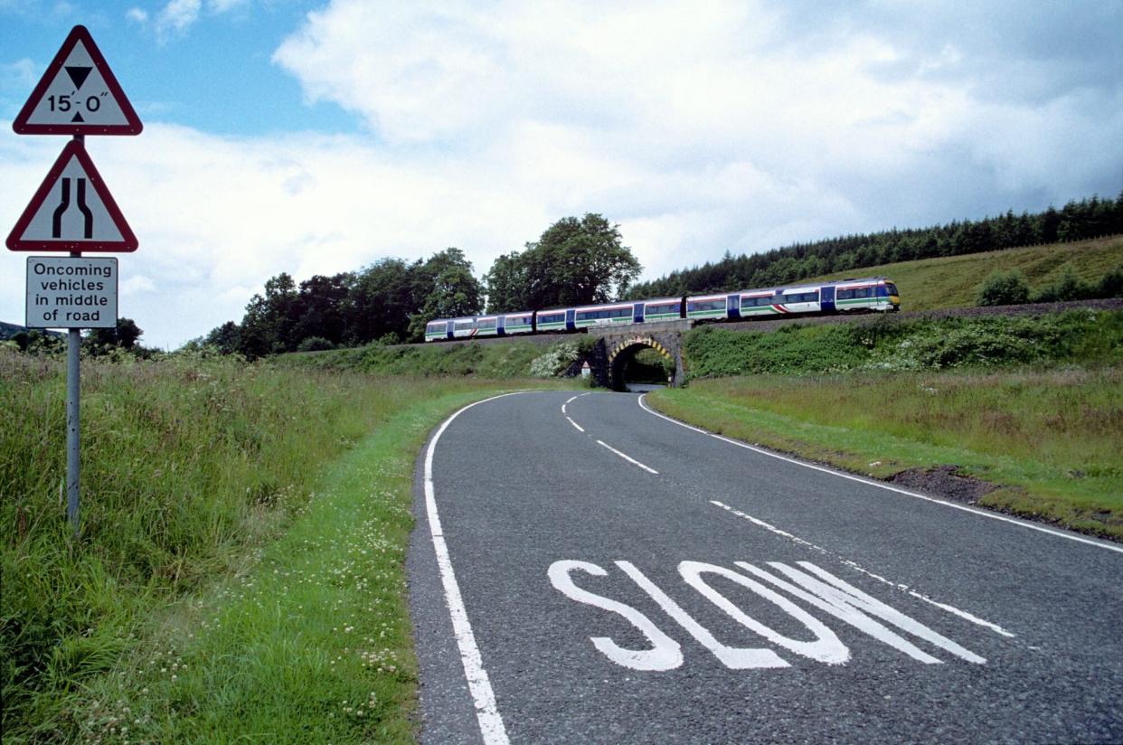 UNITED KINGDOM - DECEMBER 21: A ScotRail Class 170, photographed in July 2002, crosses the overbridge that carries the Highland main line over the B8079 near Calvine. The B8079 was formerly the route of the A9 from Calvine to Killecrankie. The A9 was upgraded during the 1970s, 80s and early 90s, but it follows essentially the same route, except where it skirts the towns and villages. Today the old A9 is a quiet back road and is used by local traffic. It also forms part of the approved route north for the Sustrans flagship project, the National Cycle Network. So far, the project has created 16,000km (9.900 miles) of signed cycle routes throughout the UK; about 70 per cent of the network is on previously existing, mostly quiet roads. The Highland Main Line is 190 km (118 miles) long and runs through the Scottish Highlands linking a series of small towns and villages with Perth at one end and Inverness at the other. Train services between Inverness and Edinburgh, Glasgow and London use the line. At Inverness the line connects with the Far North Line, the Aberdeen-Inverness Line and services on the Kyle of Lochalsh Line. Much of the Highland Main Line is single track, and trains coming in opposite directions are often timed to arrive at stations at the same time, where short stretches of double track permit them to pass. Journey times between Inverness and Edinburgh or Glasgow are approximately four hours. The vast majority of the line was built and operated by the Highland Railway with a small section of the line between Perth and Stanley built by the Scottish Midland Junction Railway, amalgamated with the Aberdeen Railway to become the Scottish North Eastern Railway in 1856, and then absorbed by the Caledonian Railway in 1866. Originally, the line between Inverness and Perth went via Forres, but the Inverness and Aviemore Direct Railway was opened in 1898 to allow for a more direct routeing. (Photo by National Railway Museum/SSPL/Getty Images)