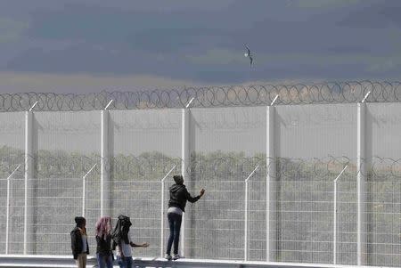 Migrants walk past the barbed wire fence on the main access route to the Ferry harbour Terminal in Calais, northern France, July 30, 2015. REUTERS/Pascal Rossignol