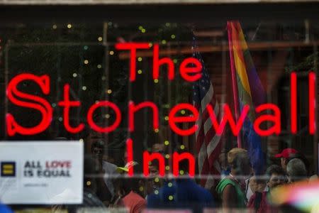 People celebrating the U.S. Supreme Court ruling against the Defense of Marriage Act can be seen reflected in the window of the Stonewall Inn in New York June 26, 2013. REUTERS/Lucas Jackson