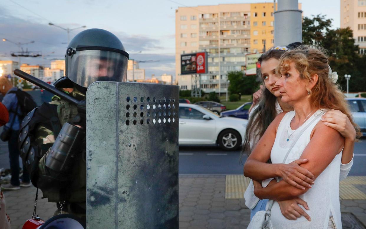 Two women talk with a riot police officer as police block a part of a street in the capital of Minsk - AP Photo/Sergei Grits
