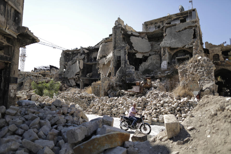 In this Saturday, July 27, 2019 photo, a man rides his motorcycle through the rubble of the old city of Aleppo, Syria. Rebels still frequently strike with shelling and mortars into Aleppo, killing civilians nearly three years after the government recaptured the city. Aleppo is a symbol of how President Bashar Assad succeeded in turning the tide in Syria’s long civil war with a series of wins, but it’s equally a symbol of how he’s been unable to secure a final victory. Half of Aleppo remains in ruins, and rebels remain on the doorstep. (AP Photo/Hassan Ammar)