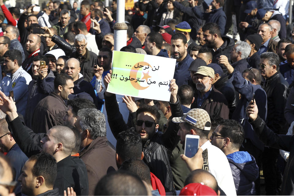 A protester holds up a sign reading "the people will not leave it's up to you to get out" during a demonstration to denounce President Abdelaziz Bouteflika's bid for a fifth term, in Algiers, Algeria, Friday, Feb. 23, 2019. The 81-year-old Bouteflika announced this month that he plans to seek a new term in April presidential elections despite serious questions over his fitness for office after a 2013 stroke left him largely infirm. (AP Photo/Anis Belghoul)