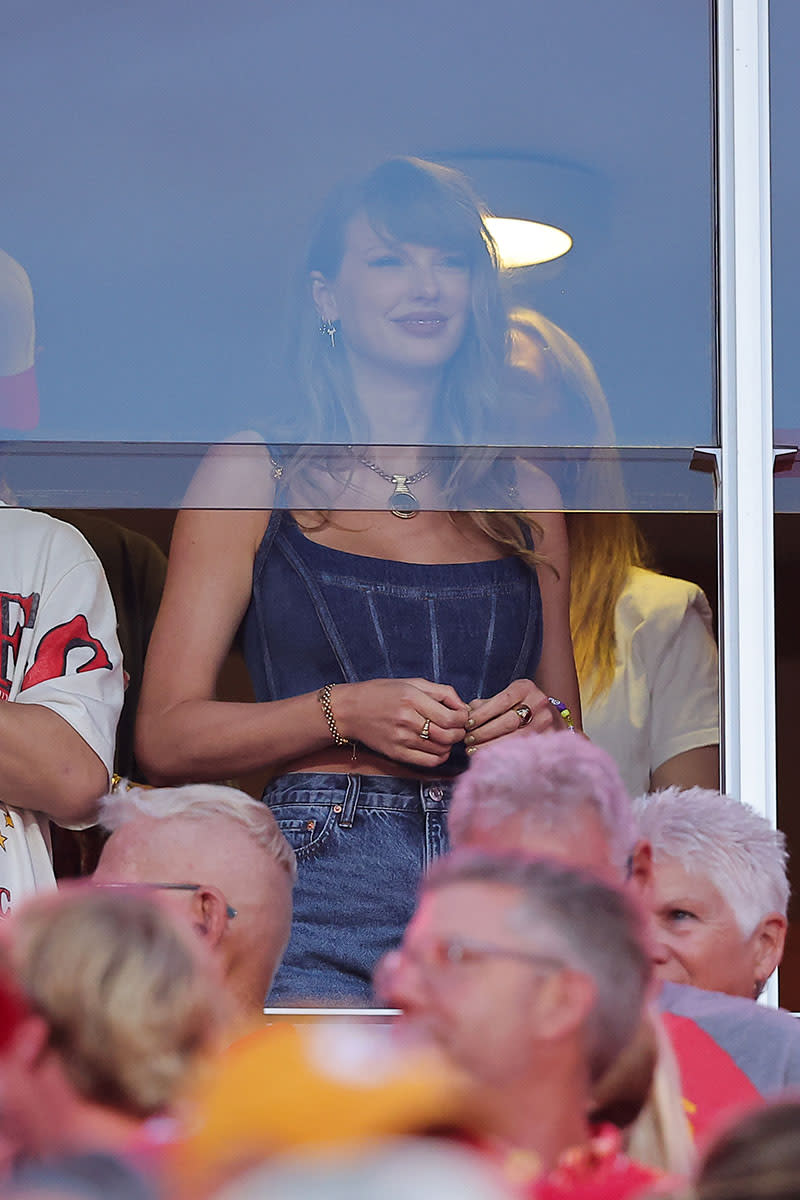 KANSAS CITY, MISSOURI – SEPTEMBER 05: Taylor Swift watches the Kansas City Chiefs take on the Baltimore Ravens during the first quarter at GEHA Field at Arrowhead Stadium on September 5, 2024 in Kansas City, Missouri. (Photo by David Eulitt/Getty Images), Lwymmd boots, red boots by Guiseppe Zanotti, Versace denim Medusa 95 bustier corset top