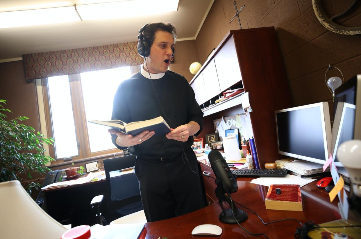 <span class="caption">The Rev. Philip Dinwiddie sings to a pre-recording of mass at St. James Episcopal Church in Grosse Ile, Michigan.</span> <span class="attribution"><a class="link " href="https://www.gettyimages.com/detail/news-photo/the-rev-philip-dinwiddie-sings-in-his-office-adding-music-news-photo/1220888445?adppopup=true" rel="nofollow noopener" target="_blank" data-ylk="slk:Gregory Shamus/Getty Images;elm:context_link;itc:0;sec:content-canvas">Gregory Shamus/Getty Images</a></span>