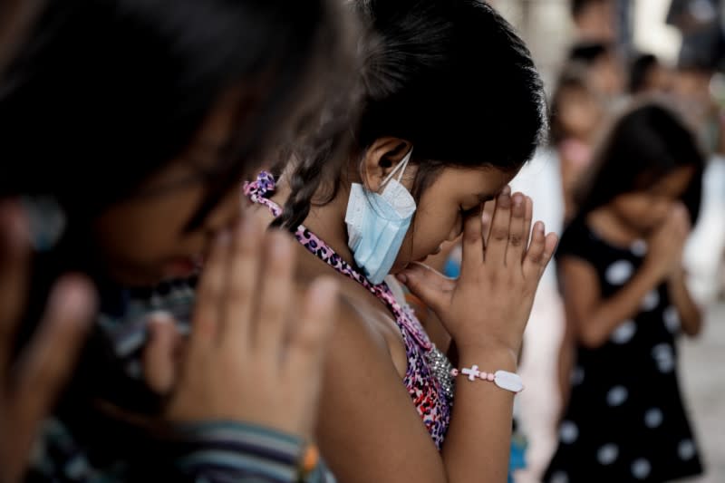 Children displaced by Taal Volcano's eruption pray solemnly during a Catholic mass in an evacuation center, in Tagaytay City