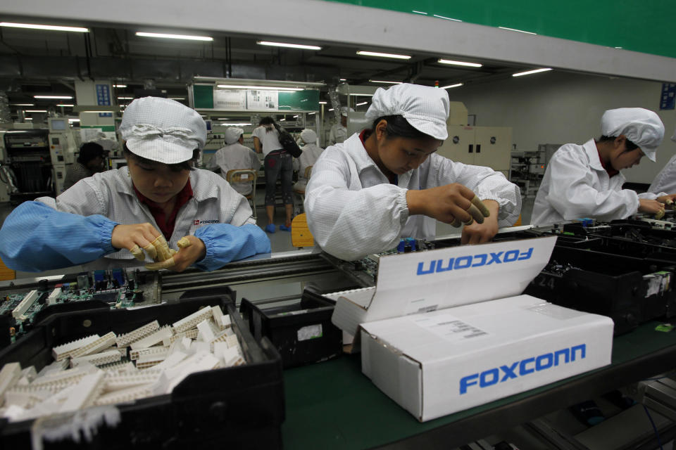 FILE - In this May 26, 2010 file photo, staff members work on the production line at the Foxconn complex in the southern Chinese city of Shenzhen, southern China. A pledge reported Thursday, March 29, 2012 by the manufacturer of Apple's iPhones and iPads to limit work hours at its factories in China could force other global corporations to hike pay for Chinese workers who produce the world's consumer electronics, toys and other goods. Foxconn Technology's promise comes as Beijing is pushing foreign companies to share more of their revenues with Chinese employees. (AP Photo/Kin Cheung, File)