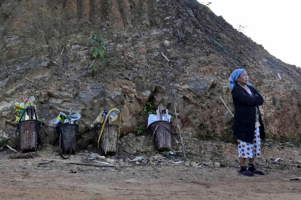 50-year-old Among, a Konyak Naga woman, stands beside woven baskets of fellow villagers as they take a rest while walking back from their fields towards Oting village, in the northeastern Indian state of Nagaland, Wednesday, Dec. 15, 2021. "If we don't go to the fields, we will die of hunger. Even Christmas will bring no joy. Our hearts are hurting. They were our own children,” Among said, referring to more than a dozen civilians killed by Indian army soldiers on Dec. 4. (AP Photo/Yirmiyan Arthur)