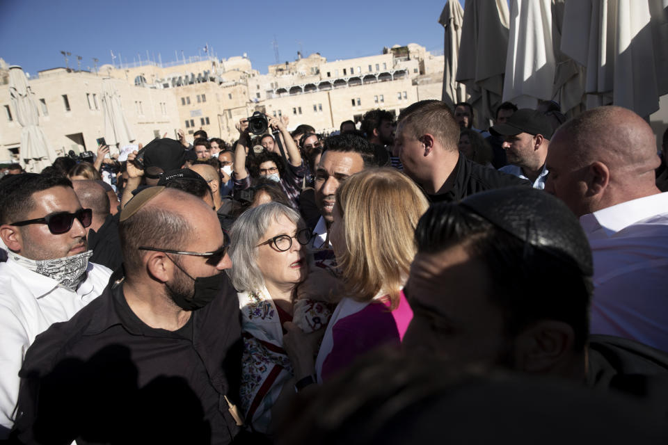 A member of the Women of the Wall, center, clutches a Torah scroll, as she is surrounded by Israeli security forces holding back protesters at the Western Wall, the holiest site where Jews can pray, in the Old City of Jerusalem, Friday, Nov. 5, 2021. Thousands of ultra-Orthodox Jews gathered at the site to protest against the Jewish women's group that holds monthly prayers there in a long-running campaign for gender equality at the site. (AP Photo/Maya Alleruzzo)