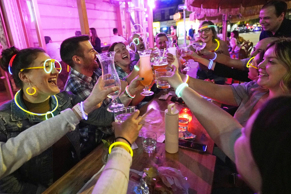 Emily Baumgartner, left, and Luke Finley, second from left, join friends from their church group in a birthday toast to one of the members, upper right, during their weekly "Monday Night Hang" gathering at the Tiki Bar on Manhattan's Upper West Side Monday, May 17, 2021, in New York. "Most of us live alone. and we need community. During the pandemic, we started hanging out in the park (Central Park) once a week. Once bars and restaurants reopened, we started coming back to Tiki Bar afterward. Under the latest regulations, vaccinated New Yorkers can shed their masks in most situations Wednesday. (AP Photo/Kathy Willens)