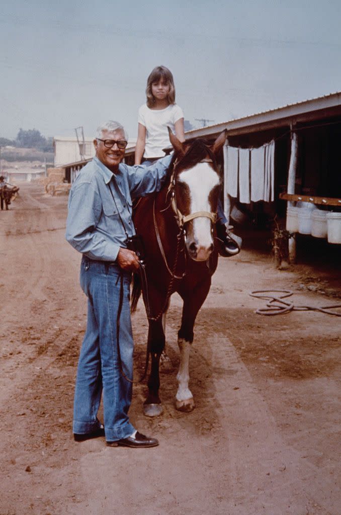 <p>Cary Grant stands next to his daughter Jennifer– his only child with ex-wife Dyan Cannon–as she rides horseback in 1976. </p>