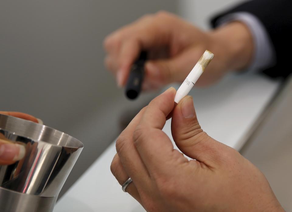 A customer takes off a filter after trying a Philip Morris' "iQOS" smokeless tobacco e-cigarette at an iQOS store in Tokyo, Japan, March 3, 2016. REUTERS/Toru Hanai