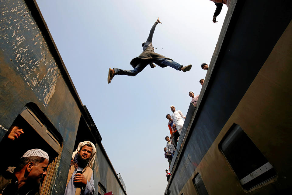 A commuter jumps between trains upon arrival at a station on the outskirts of Dhaka