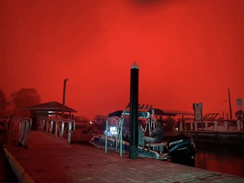 A family boards a boat to escape bushfires in Mallacoota - Credit: BRADLEY DEACON/TWITTER