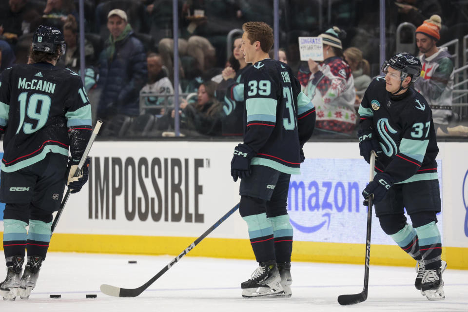 Seattle Kraken defenseman Ryker Evans (39) warms up with left wing Jared McCann (19) and center Yanni Gourde (37) for the team's NHL hockey game against the New Jersey Devils on Thursday, Dec. 7, 2023, in Seattle. (AP Photo/Jason Redmond)