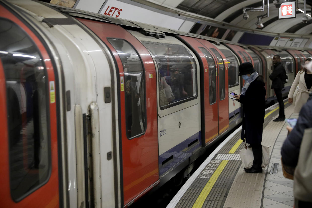 A woman wearing a face mask waits to board an underground train on the Central Line at Bank station in London, Wednesday, March 4, 2020. British authorities laid out plans Tuesday to confront a COVID-19 epidemic, saying that the new coronavirus could spread within weeks from a few dozen confirmed cases to millions of infections, with thousands of people in the U.K. at risk of death. (AP Photo/Matt Dunham)