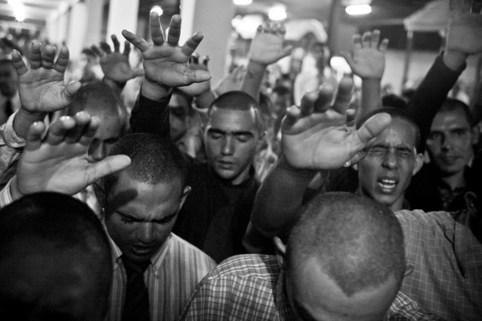 Prisoners hold their hands out in prayer.