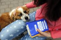 Ana-Maria Ciulcu holds European Union pets passports in Bucharest April 12, 2014. Ana-Maria is just 13 years-old and she had the idea of using social media to find people willing to adopt a stray dog. Different from other children her age, she uses all her free time to save stray dogs. Her Facebook page turned into an adoption centre, very successful until now, with more than 150 dogs sent abroad to animal lovers mainly from Germany, Austria and Belgium. Picture taken April 12, 2014. REUTERS/Bogdan Cristel (ROMANIA - Tags: ANIMALS SOCIETY)