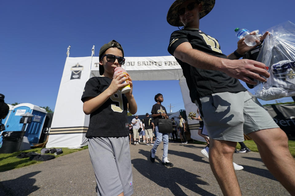 Orlan Lockhart, of Prairieville, La., enters the grounds with his son Orlan Lockhart, Jr., 5, at the start of the Back Together Weekend fan appreciation initiative at the New Orleans Saints NFL team's football training camp in Metairie, La., Saturday, July 29, 2023. (AP Photo/Gerald Herbert)