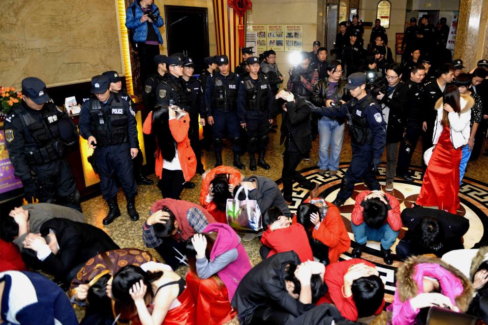 Police conduct a head count of suspects who were detained during a police raid, as part of plans to crackdown on prostitution, at a hotel in Dongguan, Guangdong province, February 9, 2014. According to Xinhua News Agency, Dongguan, a booming entertainment hub of southern China, launched a crackdown on underground prostitution on Sunday following the week-long Spring Festival holiday. Picture taken February 9, 2014. REUTERS/China Daily (CHINA - Tags: CRIME LAW) CHINA OUT. NO COMMERCIAL OR EDITORIAL SALES IN CHINA