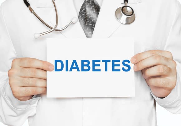 A doctor holding a sign that reads diabetes.