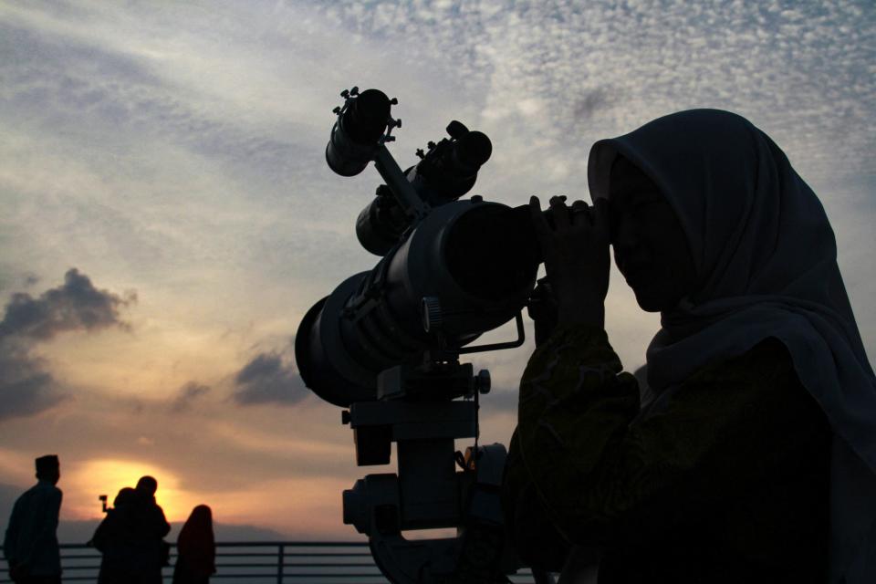 A Muslim woman looks through a telescope for sighting of the new moon at sundown to mark the start of Islam's holy fasting month of Ramadan in Medan on March 10, 2024.