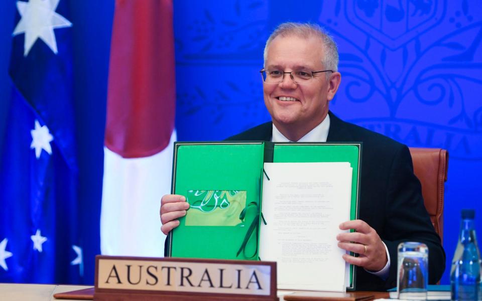 Scott Morrison holds up his signed document as Australia signs a defence deal with Japan - Lukas Coch/AAP Image via AP/AP