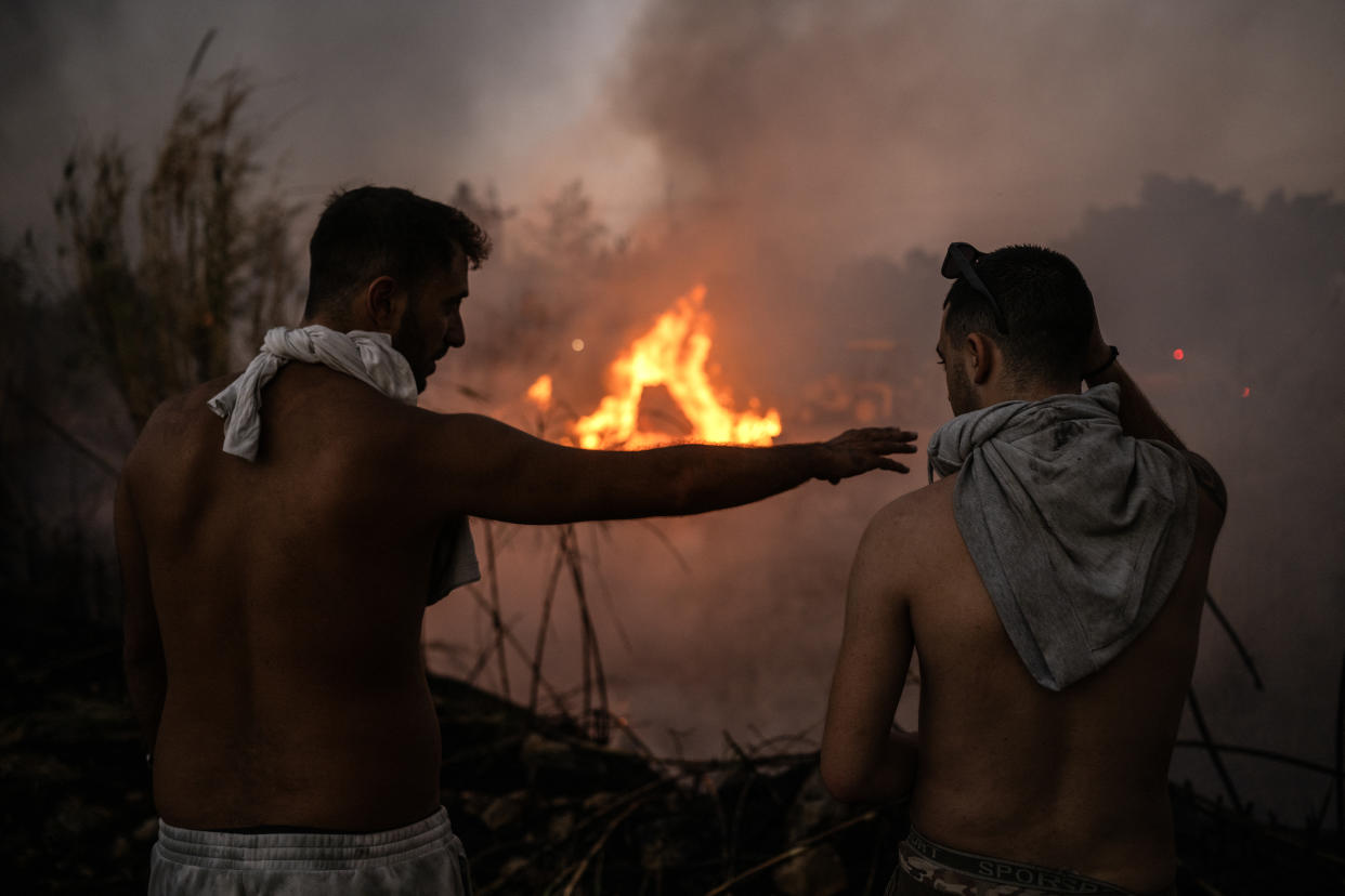 Volunteers stand in front of a small pocket of fire near Penteli, Greece, on Monday. 