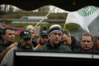 Farmers watch French Prime Minister Gabriel Attal announcing new measures for farmers on a blocked highway, Thursday, Feb.1, 2024 in Chilly-Mazarin, south of Paris. Protests have been held across the EU for most of the week and hundreds of angry farmers driving heavy-duty tractors arrived at European Union headquarters, bent on getting their complaints about excessive costs, rules and bureaucracy heard and fixed by EU leaders at a summit Thursday in Brussels, Belgium. (AP Photo/Christophe Ena)