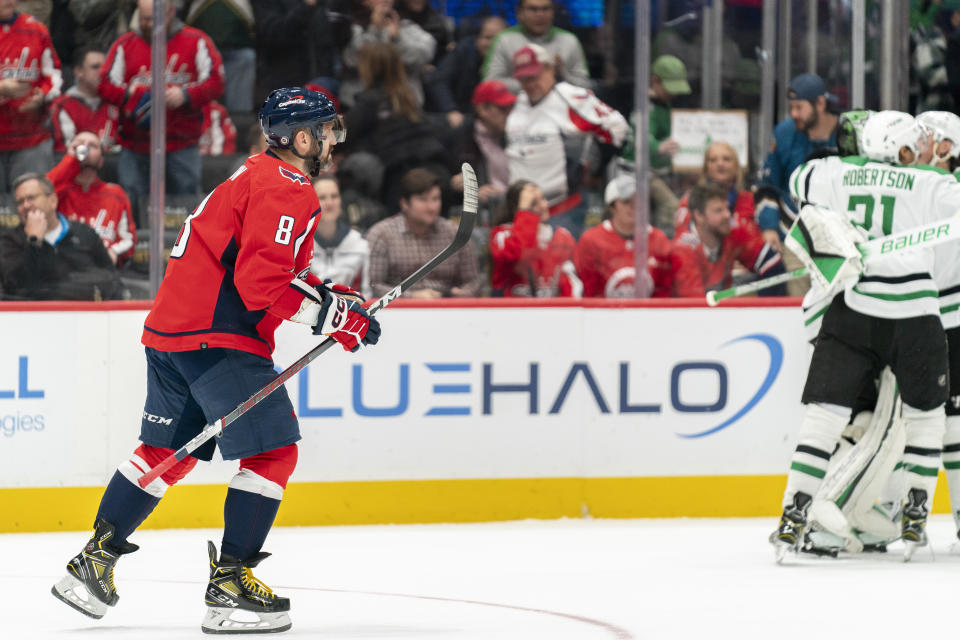 Washington Capitals left wing Alex Ovechkin (8) returns to the bench after missing a shot in an overtime shootout of an NHL hockey game while the Dallas Stars celebrate their win Thursday, Dec. 7, 2023, in Washington. (AP Photo/Stephanie Scarbrough)