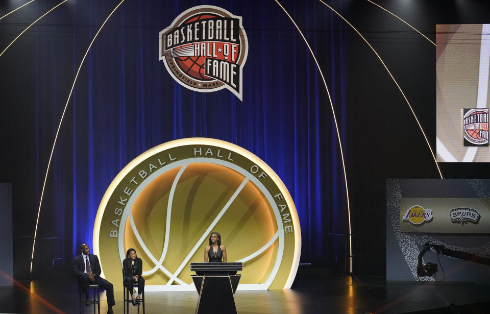 Tamika Catchings speaks while being inducted with 2020 Basketball Hall of Fame class, Saturday, May 15, 2021, in Uncasville, Conn. Catchings' presenters, Alonzo Mourning, left, and Dawn Staley, second from left, listen. (AP Photo/Kathy Willens)