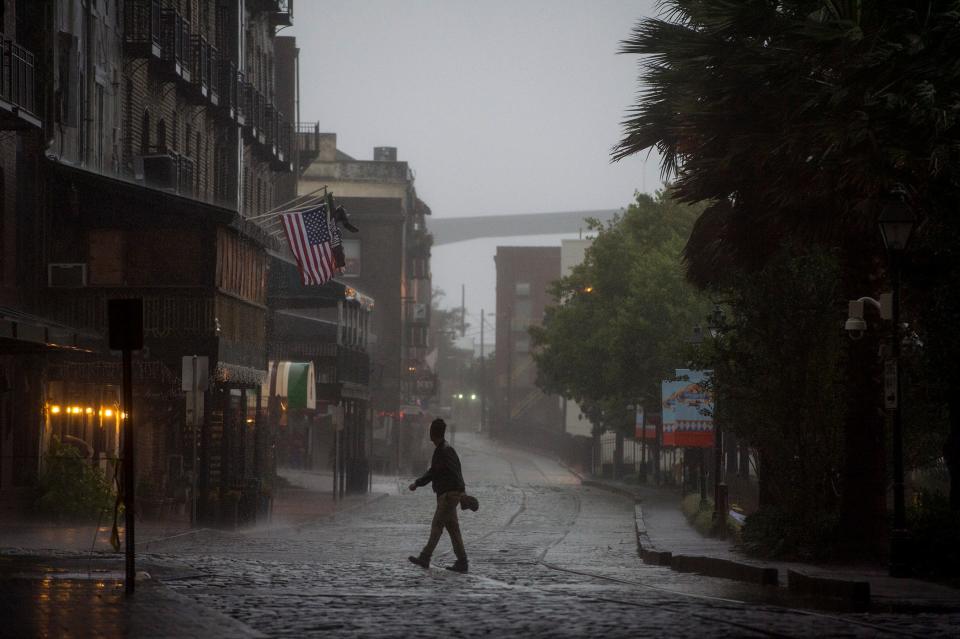 A man walks across River Street during the storm caused by Hurricane Matthew Friday afternoon.