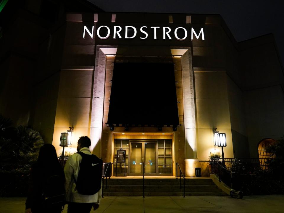 Exterior of Nordstrom store lit up at night with person walking toward it