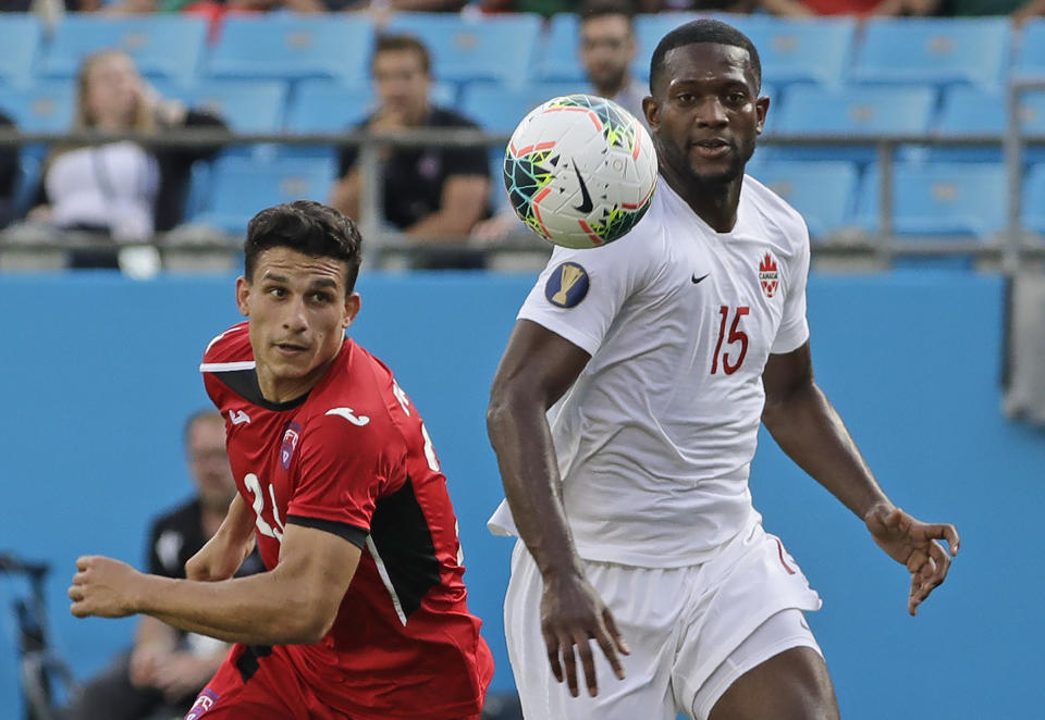 Canada's Doneil Henry (15) and Cuba's Luis Paradela (23) chase the ball during the first half of a CONCACAF Golf Cup soccer match in Charlotte, N.C., Sunday, June 23, 2019. (AP Photo/Chuck Burton)