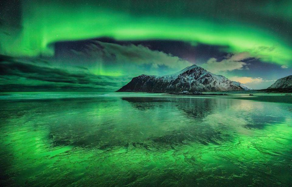 Una vívida aurora sobre la playa de Skagsanden, Islas Lofoten, Noruega.