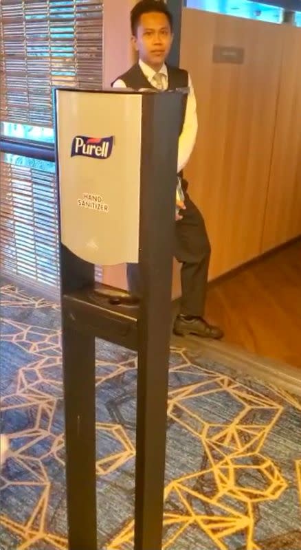 A crew member of Holland America's cruise ship MS Westerdam is seen near a hand sanitizer dispenser stand on the vessel